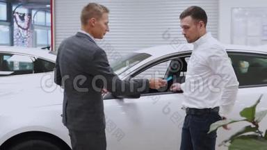 男子手把车钥匙交给男子手在汽车经销店关门。 <strong>汽车销售</strong>商和一个买车的男人